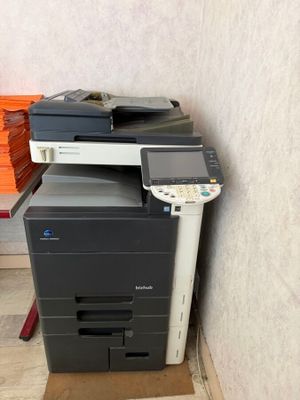 une imprimante multifonction posée par terre à côté d'une pile de livres