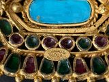 a gold brooch with a turquoise stone in it