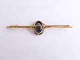 yellow gold plated brooch with a black stone in the center
