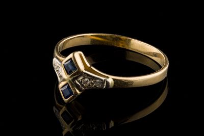 un gros plan d'une bague en or sertie d'un diamant et d'un saphir bleu