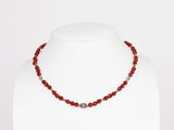 un gros plan d'un collier sur un mannequin, orné de perles rouges