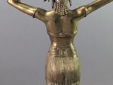 bronze statue of a woman in a skirt with her hands on her head