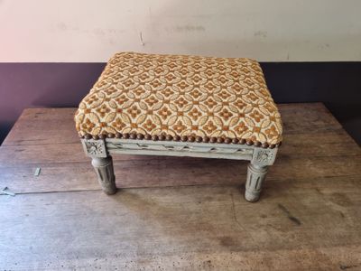 a small stool with a woven seat on top of a wooden table