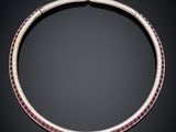 a silver necklace with pink stones on a black background