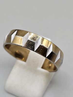gros plan d'une bague en or et en argent sur une surface blanche