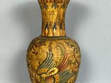 un vase jaune orné d'un oiseau, posé sur une table