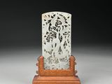 une plaque de jade blanc posée sur un socle en bois, elle-même posé sur une surface blanche