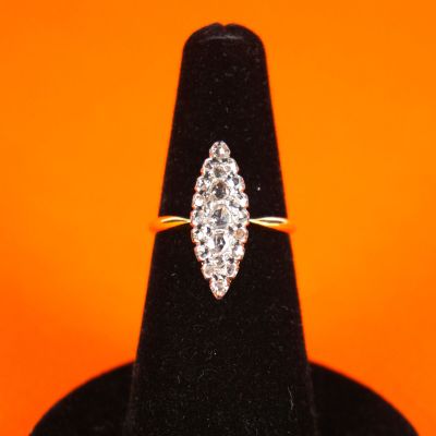 a diamond ring on a black ring stand against an orange background