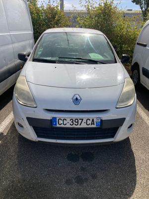 La voiture blanche est garée sur le parking, à côté de la camionnette blanche.