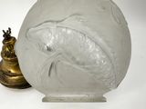 a glass vase with a fish on it next to a brass lamp
