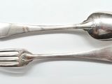 two spoons and a fork on a white surface