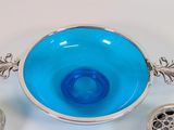 a blue glass bowl with a silver handle and spoons next to it
