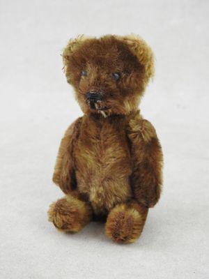 un ours en peluche marron assis sur une surface blanche