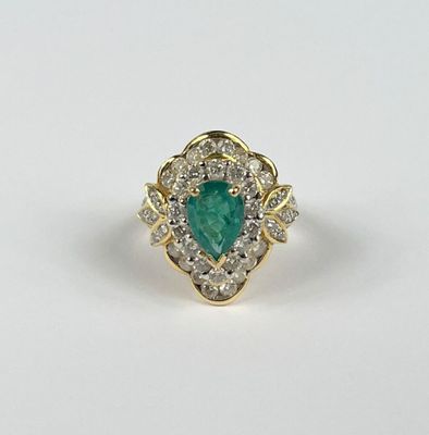 gros plan d'une bague en diamant et émeraude sur une surface blanche