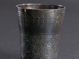 an old silver cup sitting on top of a black table