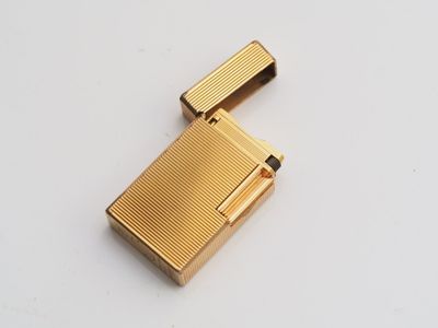 an image of a gold lighter sitting on top of a white table