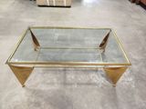 une table basse en verre avec des pieds dorés et un plateau en verre