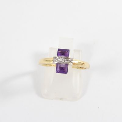 a close up of a gold ring with a purple stone and a diamond