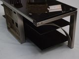 une table en verre avec un plateau noir posé sur un socle blanc