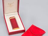 une image représentant une boîte rouge contenant un briquet plaqué or