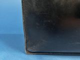 an old black leather purse sitting on top of a blue surface
