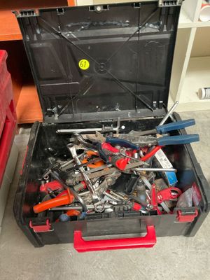 une boîte à outils remplie d'outils, posée par terre
