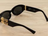 the sunglasses are black with gold lettering on them on a wooden surface