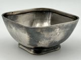 un bol ancien en argent à base carrée, posé sur une surface blanche