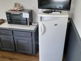 a small kitchen with a refrigerator, microwave, and a television
