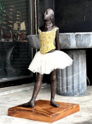 a statue of a little girl in a tutu on a wooden base