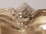 a silver sculpture of a winged head on top of a bowl