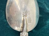 a silver spoon with a bird on it next to a silver spoon with a bird on it