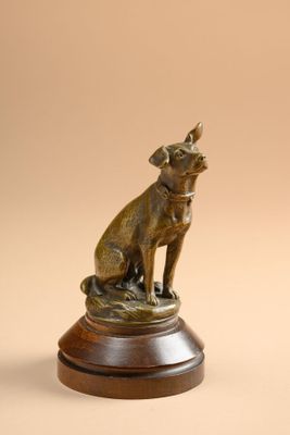 bronze statue of a dog sitting on top of a wooden base