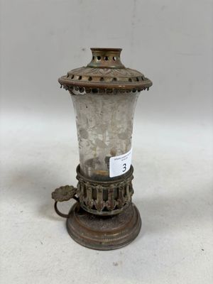 Une lampe à l'ancienne est posée sur une table, avec une étiquette dessus.