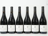 six bouteilles de vin sont alignées sur une surface blanche