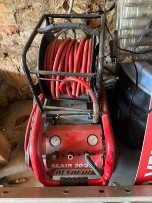 an image of a red air compressor sitting on top of a metal shelf