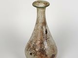 un petit vase en verre posé sur une surface blanche
