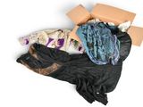 un tas de vêtements et une boîte posés sur une surface blanche