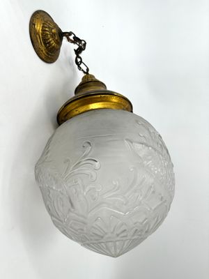 un luminaire à l'ancienne, muni d'un abat-jour en verre, suspendu au mur
