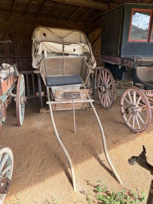une calèche garée dans une grange avec d'autres calèches