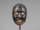 a wooden mask on a stand with a gray background