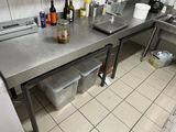 un plan de travail en acier inoxydable sur lequel sont posées des bouteilles et des récipients, dans une cuisine professionnelle