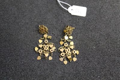 a pair of gold tone earrings on a black surface
