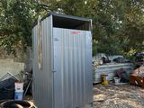 une cabane de toilettes en métal installée au milieu d'une cour