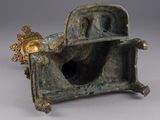 statue en bronze représentant un homme assis sur une chaise, coiffé d'un chapeau