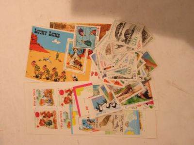 a pile of stamps on a table with a person holding a cell phone
