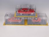 three toy cars in a display case on a white surface