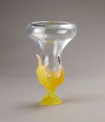 a glass vase with a yellow flower inside of it on a white surface