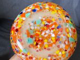 a person holding a colorful glass bowl with confetti sprinkles on it