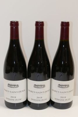 trois bouteilles de vin sont alignées sur une table